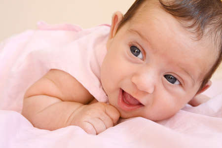 newborn girl smiling on a pink blanket
