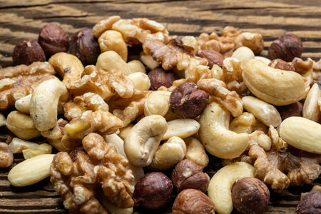 Mix of tasty nuts on a wooden surface. Cashews, almonds, hazelnuts and walnuts on a brown table.の写真素材