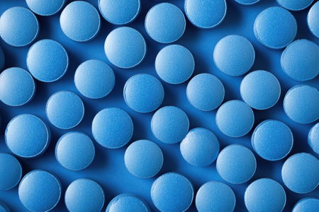 Blue pills arranged on a blue background creating a visually appealing texture, ideal for medical or healthcare-related projectsの素材