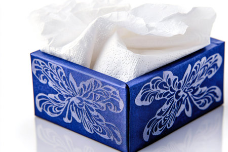 White tissues emerging from an elegant blue tissue box adorned with a beautiful floral design, adding a touch of sophisticationの素材
