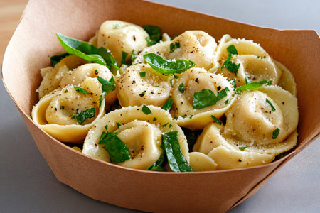 Delicious tortellini seasoned with parmesan, black pepper and basil, served in a takeaway boxの素材
