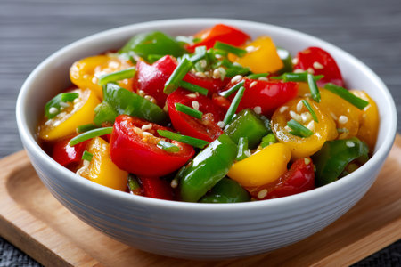 Mixed colorful bell pepper salad with chives and sesame seeds in a bowl, healthy eating conceptの素材