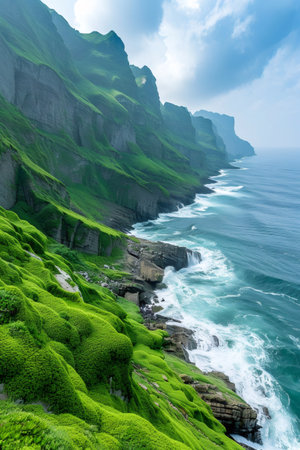 Green cliffs meeting the turbulent blue ocean along a rugged coastlineの素材