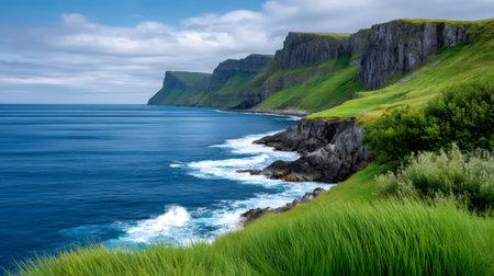 Dramatic coastline with steep green cliffs overlooking the deep blue sea and waves crashing on the shoreの素材