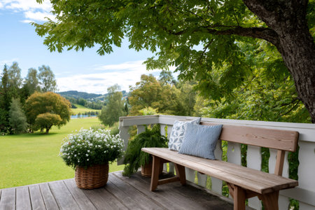 Bench with cushions on a porch enjoying a serene countryside view with trees and a lakeの素材