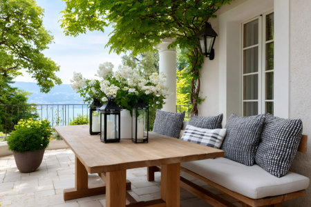 Elegant outdoor patio space featuring a wooden dining table, a comfortable bench, and lanterns with a lake viewの素材