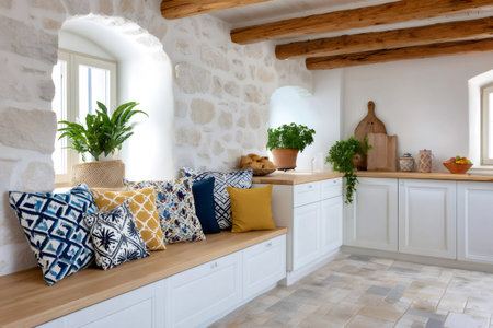 Kitchen interior featuring a stone wall, wooden beams, whitewashed cabinets, and cushioned seatingの素材