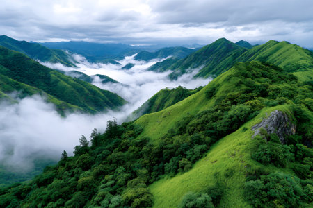Green mountains rising above a valley filled with rolling mist and cloudsの素材