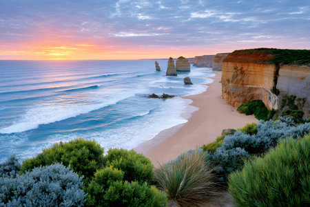 Ocean waves washing sandy beach at dawn with rock stacks and cliff coastlineの素材