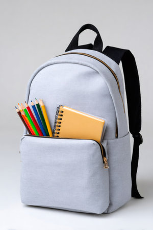 Gray backpack filled with colorful pencils and a notebook, ready for schoolの素材