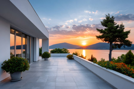 Modern villa terrace overlooking a beautiful sea bay at sunset providing a peaceful holiday conceptの素材