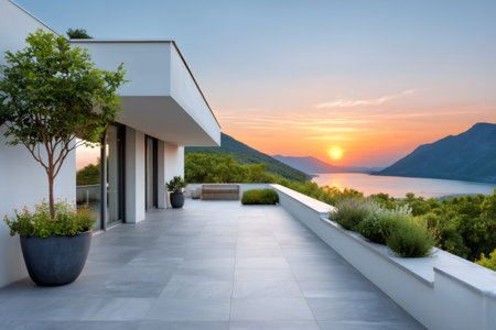 Modern house terrace enjoying sunset view over a lake surrounded by mountains and green treesの素材