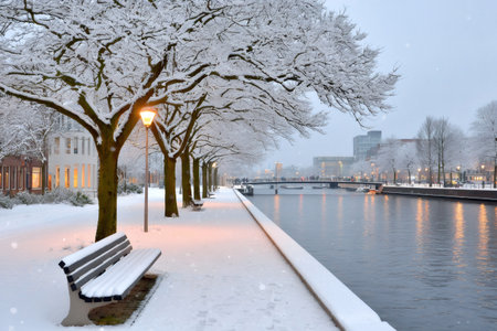 City canal scene with snow-covered trees, benches, and glowing street lights at duskの素材