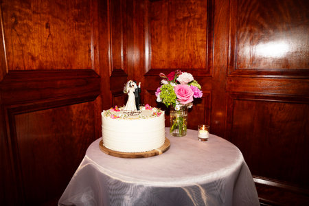 Wedding cake decorated with flowers and candles on a wooden tableの写真素材