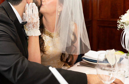 Wedding couple sitting at the table and kissing. Bride and groomの写真素材
