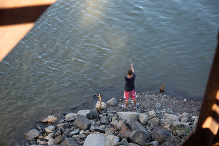 Man fishing on the river with a fishing rod in summer dayの写真素材