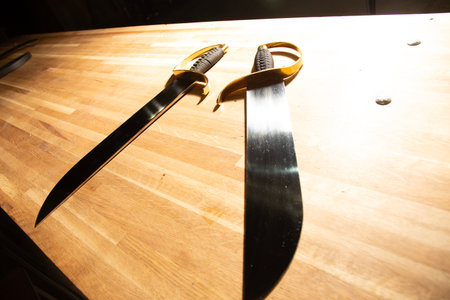 Two swords on a wooden table, closeup of photoの写真素材