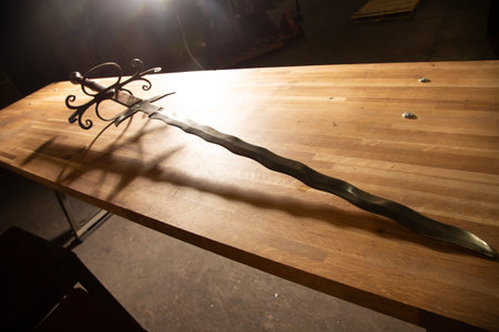 Old wooden table with a sword in a workshop. Selective focus.の写真素材