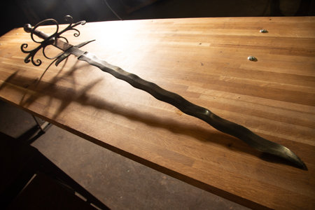 Ancient saber on a wooden table in the light of the sunの写真素材