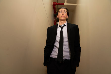 Businessman in a black suit and tie standing in an office hallwayの写真素材