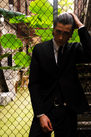 Portrait of a young man in a black suit standing in an abandoned buildingの写真素材