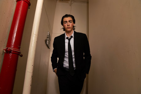 Portrait of a handsome man in a black suit posing in the roomの写真素材