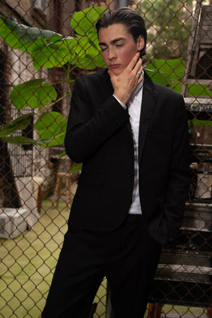 Businessman in black suit and white shirt standing in front of the fenceの写真素材