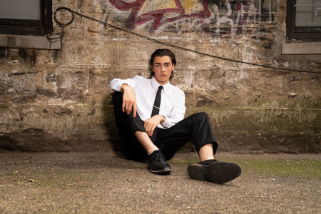 Portrait of a young businessman sitting on the ground in an urban environmentの写真素材