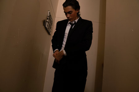 Young man in a black suit with a tie in a dark room