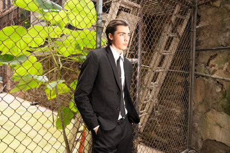 Portrait of a young businessman in a business suit standing by the fenceの写真素材