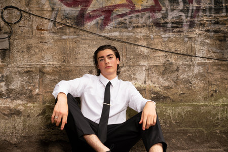 Portrait of a young businessman sitting on a wall in the cityの写真素材
