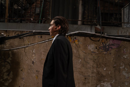 Young man in a business suit in an industrial area. Looking away.