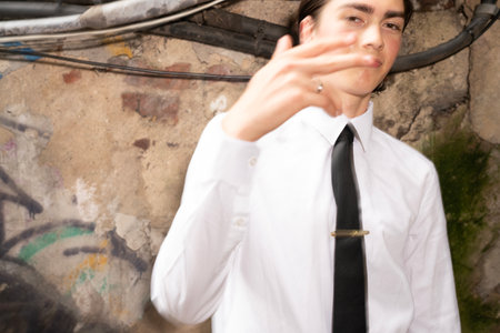 Portrait of a young businessman in white shirt and black tie standing near the wallの写真素材