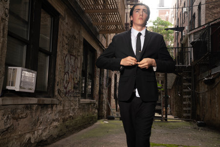 Businessman in black suit and tie standing in an old street.の写真素材
