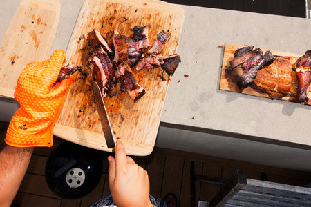 Chef cutting meat on a wooden board at a barbecue party.の写真素材