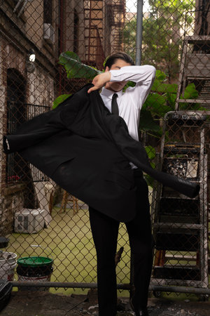 Businessman in black suit covering his face with a black jacket.の写真素材