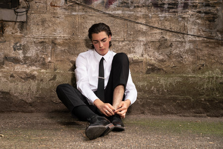 Young businessman sitting on the ground and tying his shoelaces.の写真素材