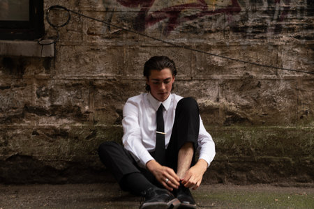 Portrait of a young businessman sitting on the ground in the cityの写真素材