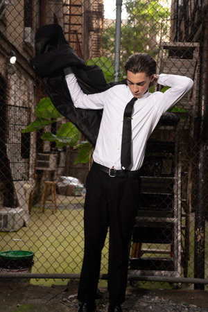 Handsome young man posing in an abandoned building, wearing a white shirt and black tie.の写真素材