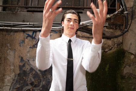 Young businessman with arms outstretched in a grunge industrial environment.の写真素材