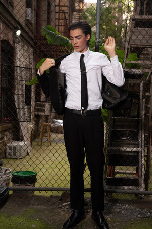 Handsome young man in white shirt and black tie posing outdoorの写真素材