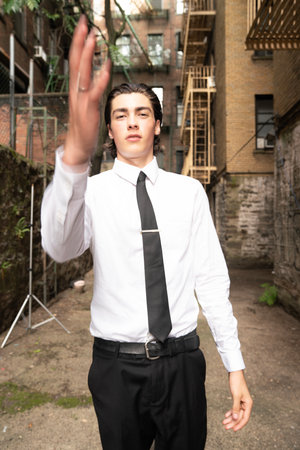 Young businessman standing in the street with his arms outstretched towards the cameraの写真素材