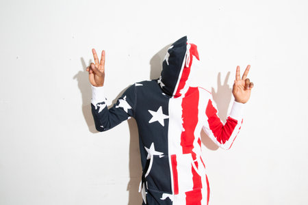 Young man in american flag suit showing victory sign with both handsの写真素材