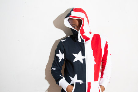 Young man wearing a hoodie with stars and stripes in a studioの写真素材