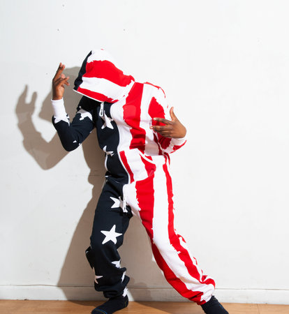 African american little boy dressed as a superhero dancing against a white wallの写真素材