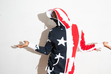 Hooded man with american flag on white background, studio shotの写真素材