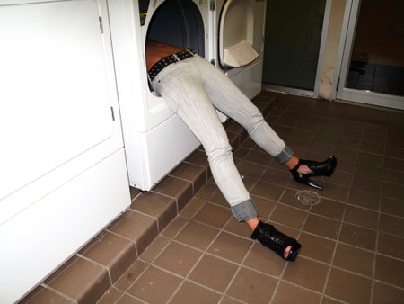 Woman sitting on the floor near the washing machine in the laundry roomの写真素材