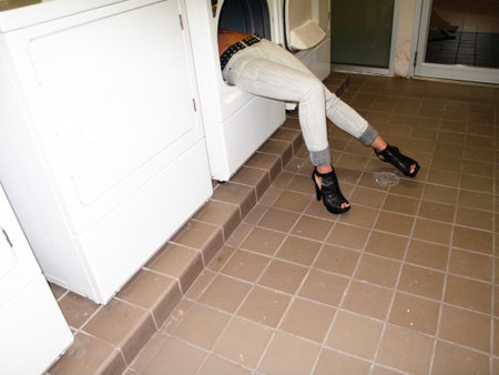 Woman putting clothes into washing machine at home.の写真素材