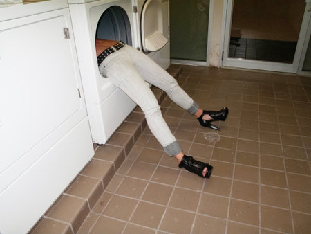 Woman sitting on the floor in front of washing machine in a bathroomの写真素材