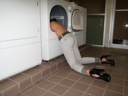 Young woman in front of the washing machine in the bathroom at homeの写真素材
